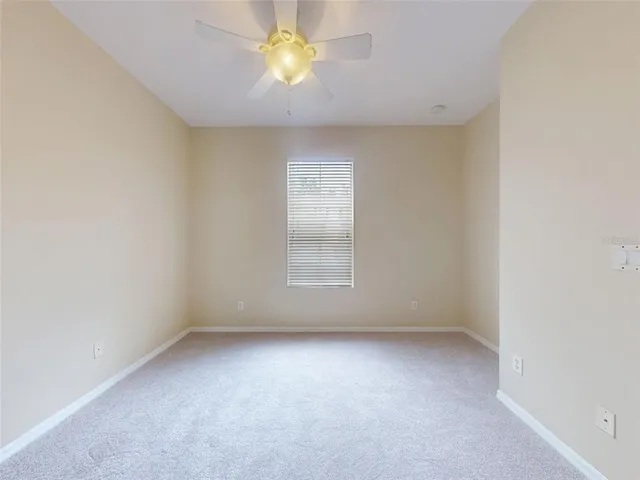an empty room with a window and a fan
