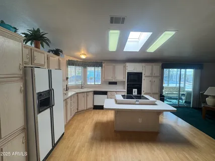 a living room with kitchen island granite countertop furniture wooden floor and a large window