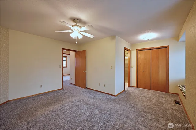 an empty room with closet and a ceiling fan