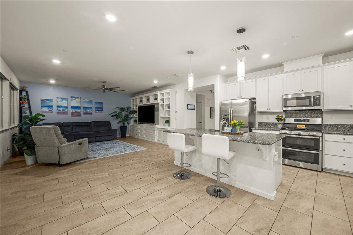12791 Evanston Way Rancho Cordova, CA 95742 - Photo 54 of 54 a large white kitchen with kitchen island a stove a sink a table and chairs