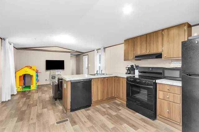 a kitchen with stainless steel appliances granite countertop a stove top oven a sink dishwasher and a refrigerator with wooden cabinets