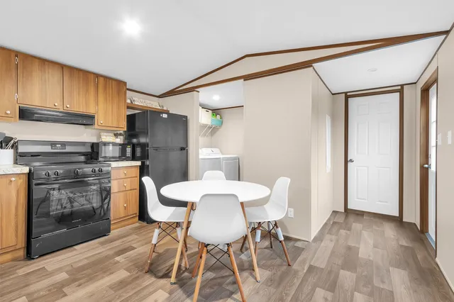 a kitchen with stainless steel appliances a refrigerator a stove a dining table and chairs with wooden floor