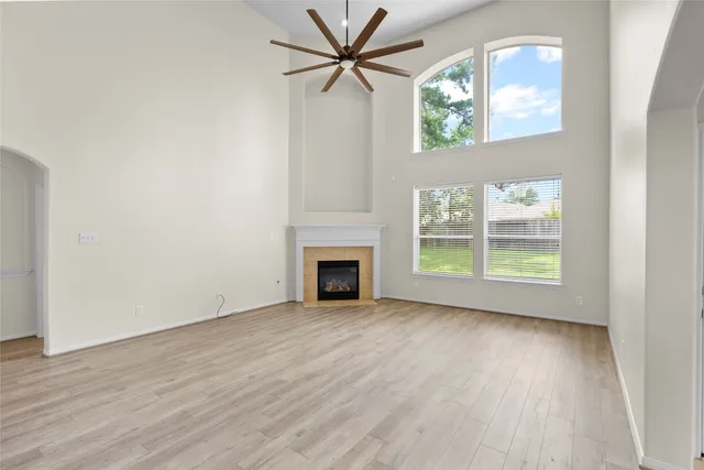 an empty room with windows fireplace and a chandelier fan