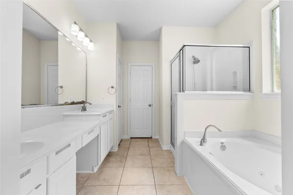 a spacious bathroom with a tub sink and mirror