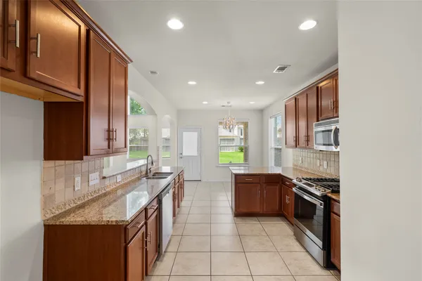 a large kitchen with stainless steel appliances granite countertop a stove a sink and a refrigerator
