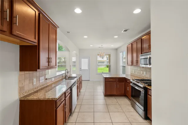 a large kitchen with stainless steel appliances granite countertop a stove a sink and a refrigerator