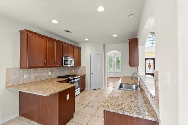 a kitchen with stainless steel appliances granite countertop a stove a sink and a microwave