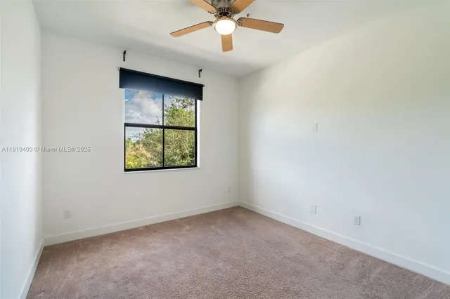 an empty room with window and ceiling fan