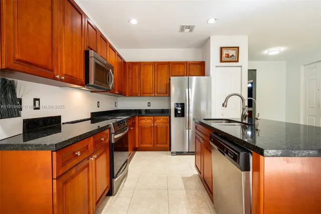 a kitchen with stainless steel appliances granite countertop a stove a sink and a refrigerator