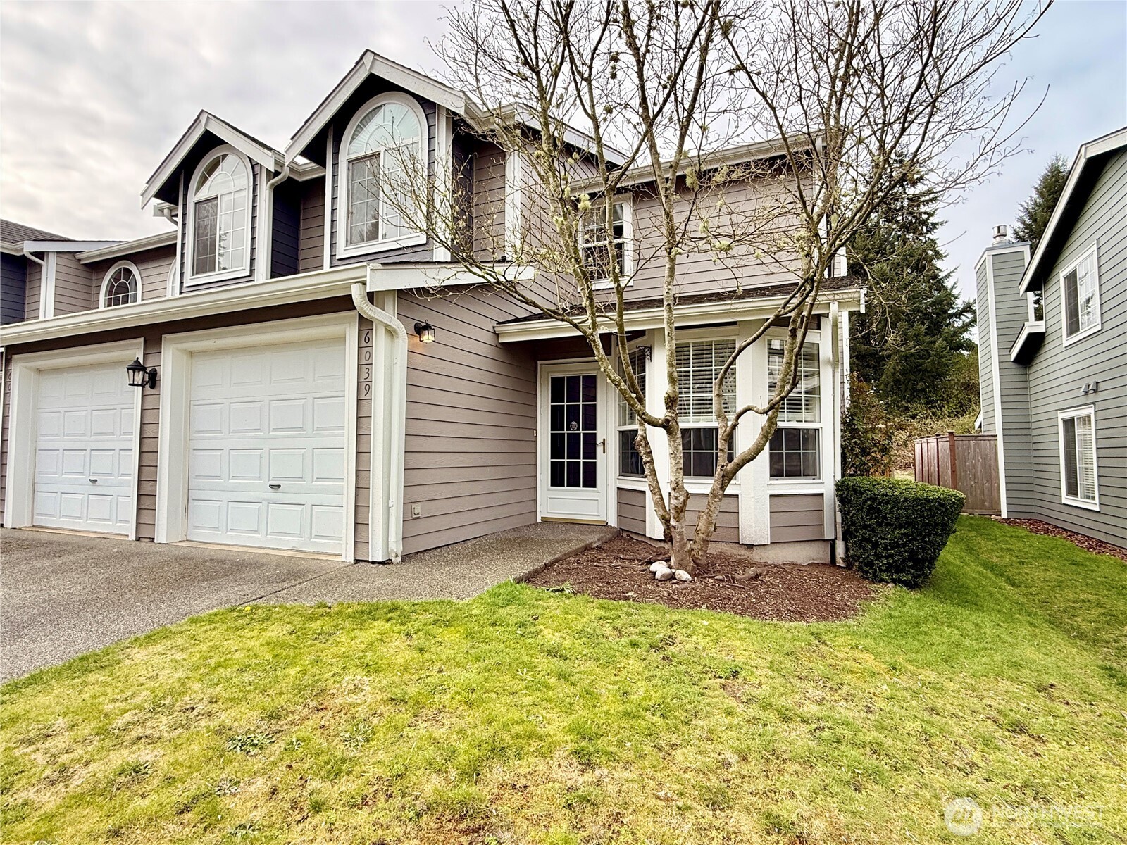 6039 Merlot Lane Southeast Lacey, WA 98513 - Photo 20 of 21 a view of a white house with large windows and a small yard