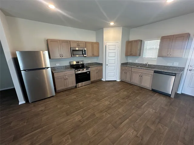 a kitchen with granite countertop a refrigerator stove top oven and sink