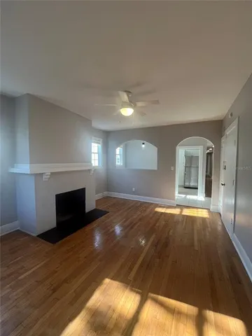 a view of empty room with wooden floor fireplace and window