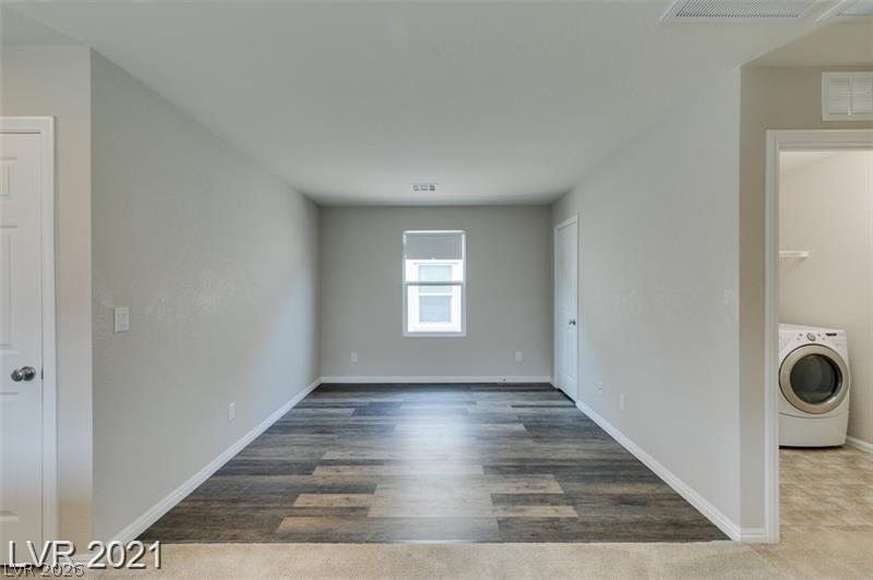 5475 Ordesa Valley Road Las Vegas, NV 89148 - Photo 20 of 35 A well-lit, neutral-toned room features attractive wood plank flooring, seamlessly transitioning to carpeting.