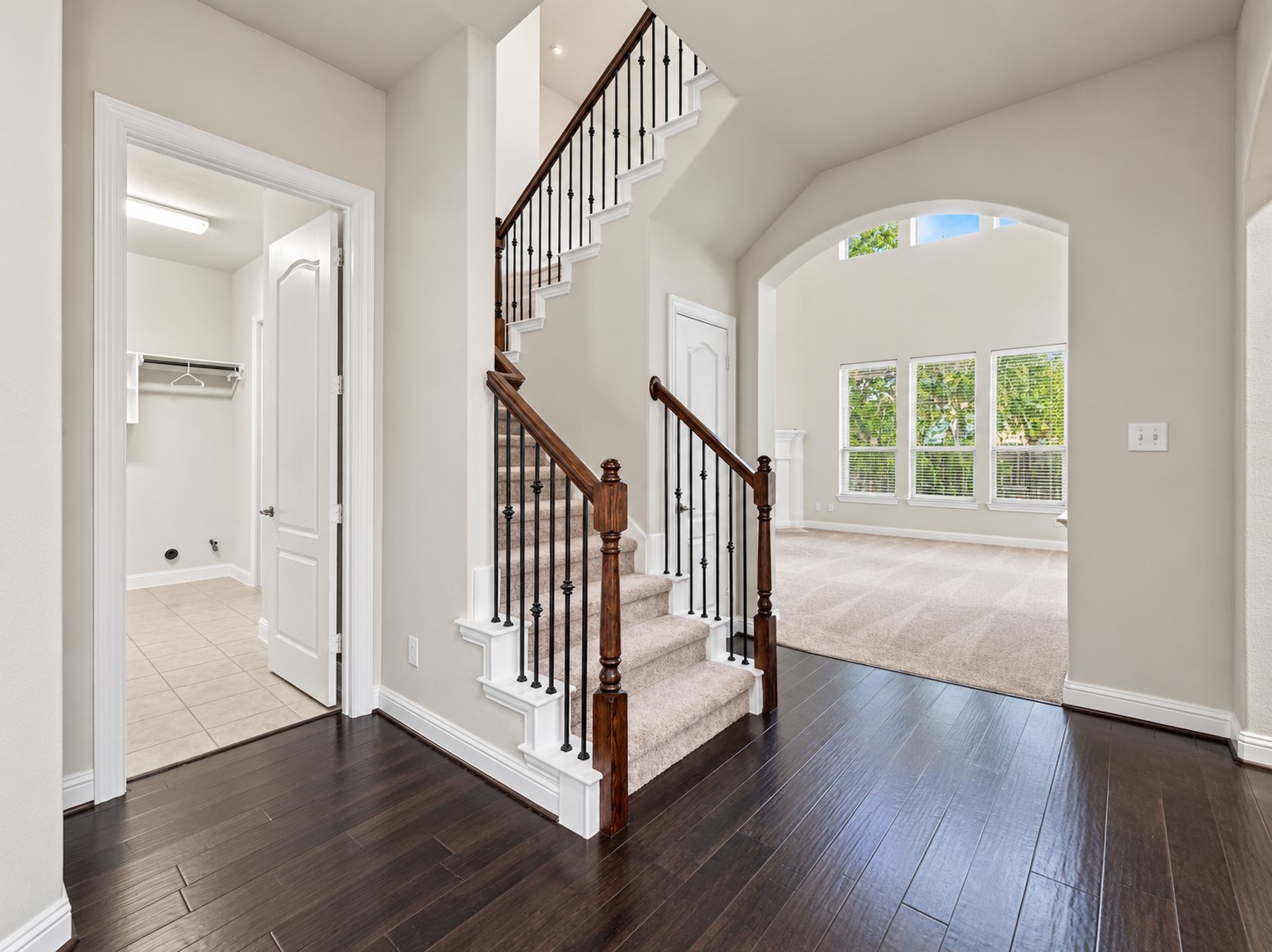 9626 Invergarry Way Tomball, TX 77375 - Photo 7 of 43 View toward the living room highlighting the staircase with wood handrails and wrought-iron balusters, arched openings, and rich wood flooring.