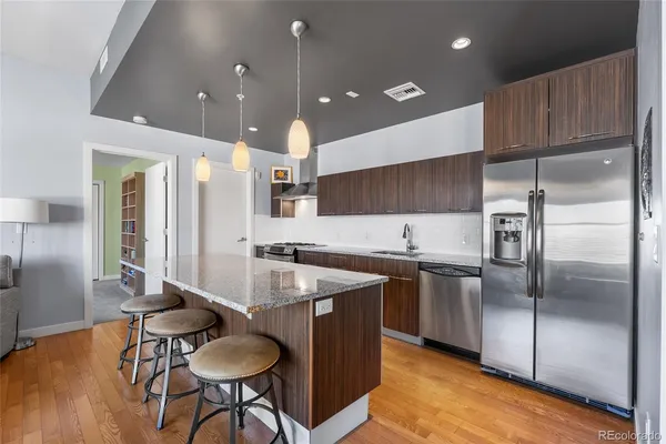 a kitchen with stainless steel appliances granite countertop a sink a stove and a refrigerator
