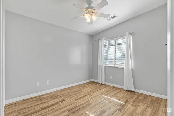 a view of empty room with wooden floor and fan