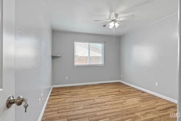 a view of a room with wooden floor and a chandelier fan