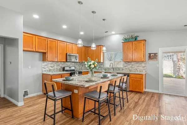 a kitchen with stainless steel appliances granite countertop wooden cabinets a dining table and chairs