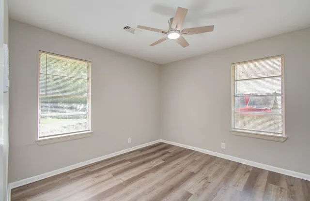 a view of an empty room with a window and wooden floor