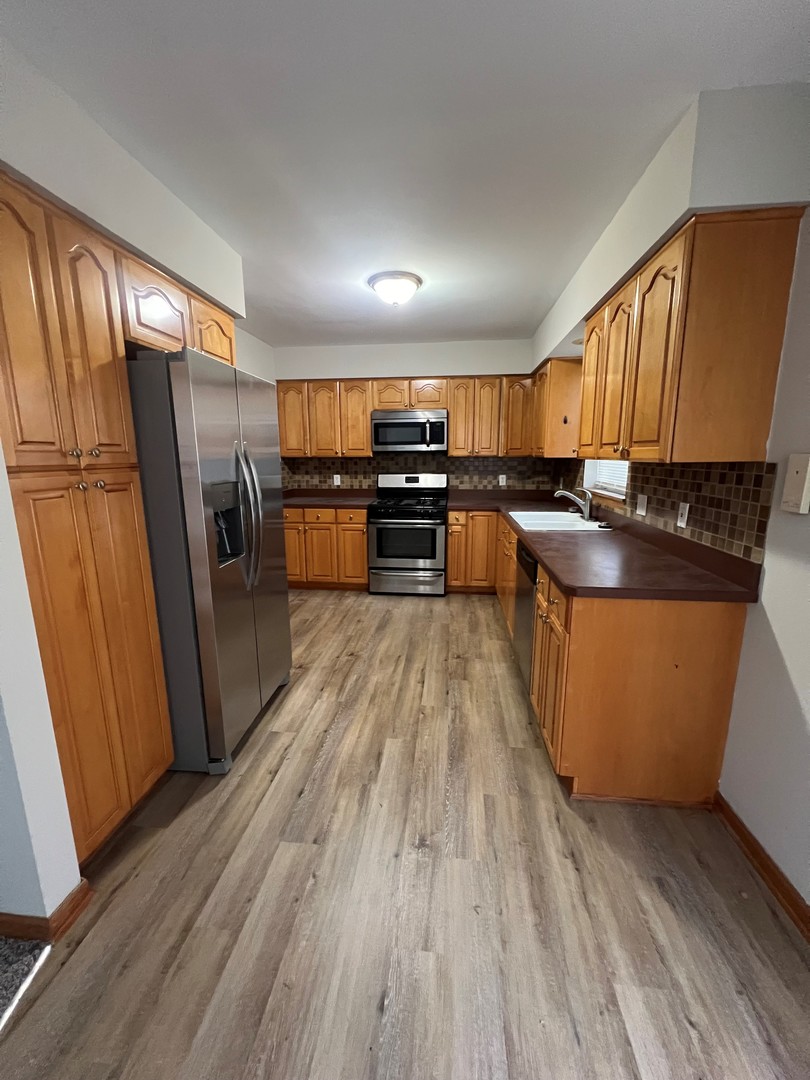 655 Nichole Lane Geneva, IL 60134 - Photo 5 of 11 a kitchen with stainless steel appliances wooden floor sink and wooden cabinets