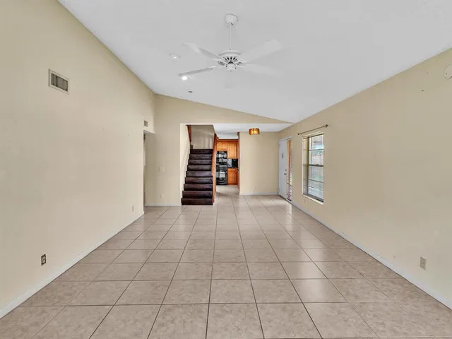 an empty room with ceiling fan and window