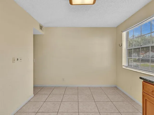 an empty room with wooden floor chandelier fan and windows