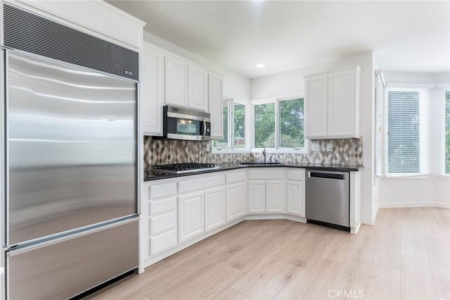 a kitchen with granite countertop white cabinets appliances and a window