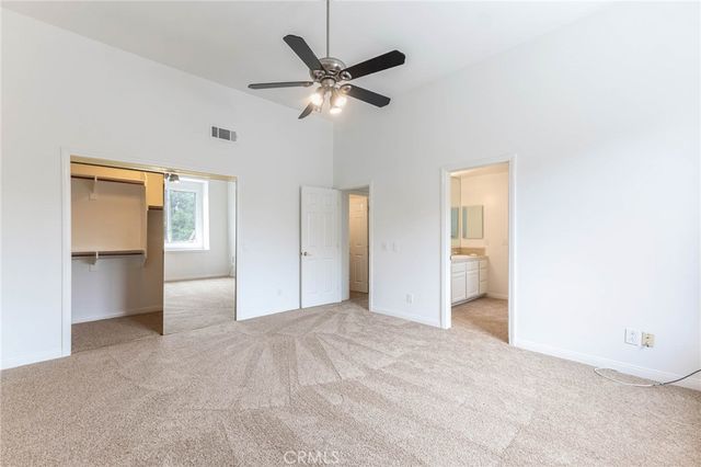 a view of a livingroom with a ceiling fan and kitchen space with wooden floor