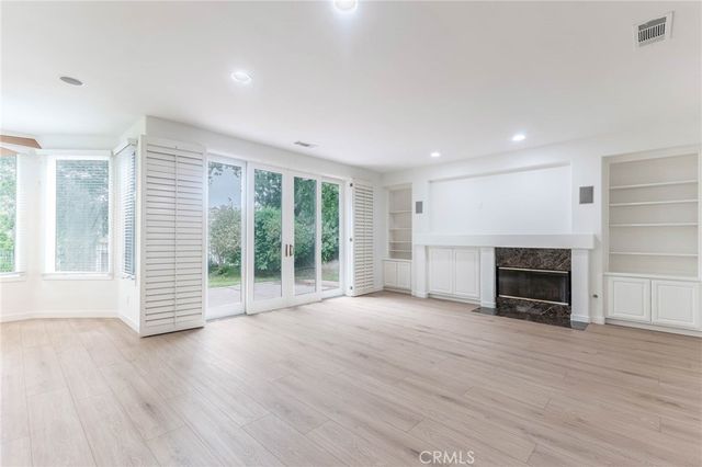 an empty room with wooden floor fireplace and windows