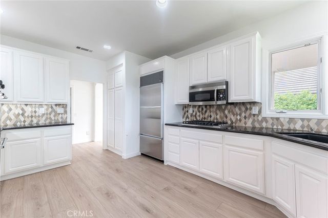 a kitchen with granite countertop white cabinets and stainless steel appliances