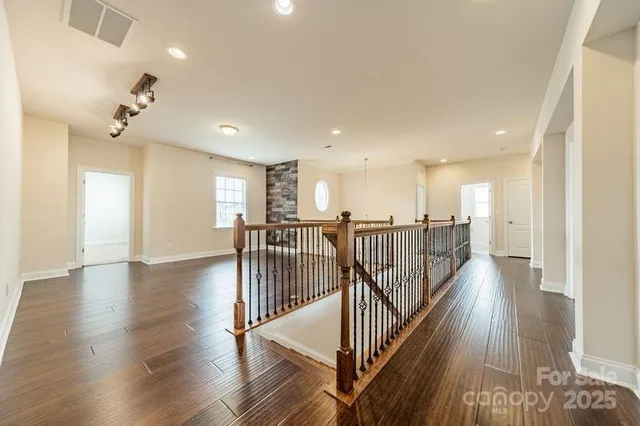 a view of a hallway with wooden floor and stairs