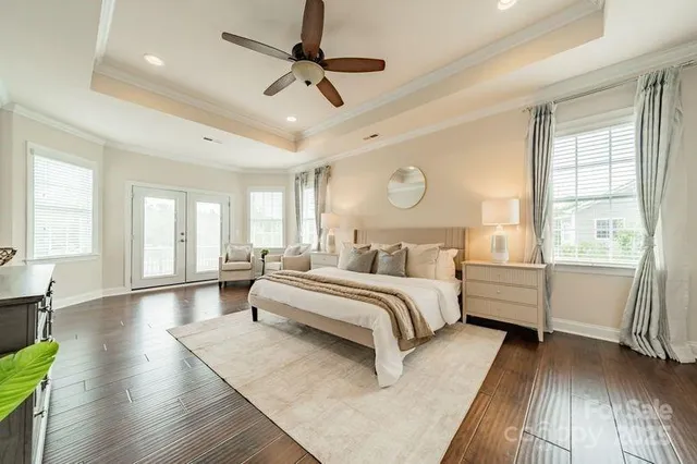 a spacious bedroom with a large bed a chandelier and windows