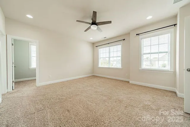 an empty room with windows and ceiling fan