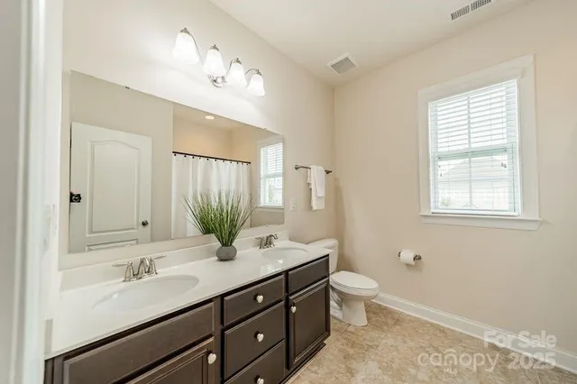 a bathroom with a double vanity sink toilet and a mirror
