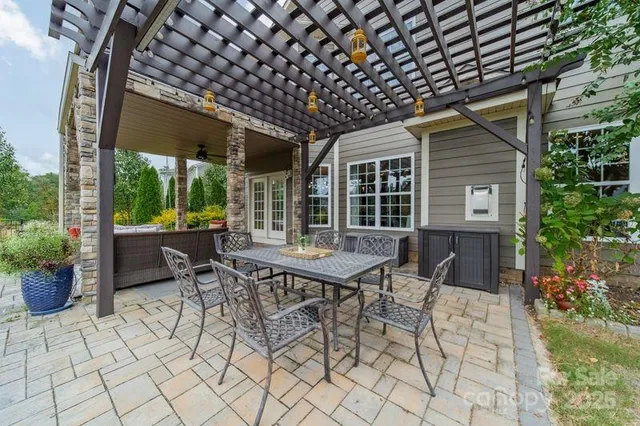 a view of a patio with table and chairs potted plants and floor to ceiling window