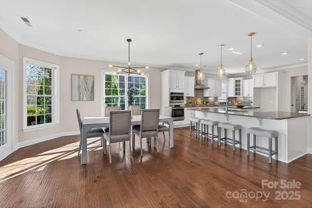 a dining room with furniture a floor to ceiling window and wooden floor