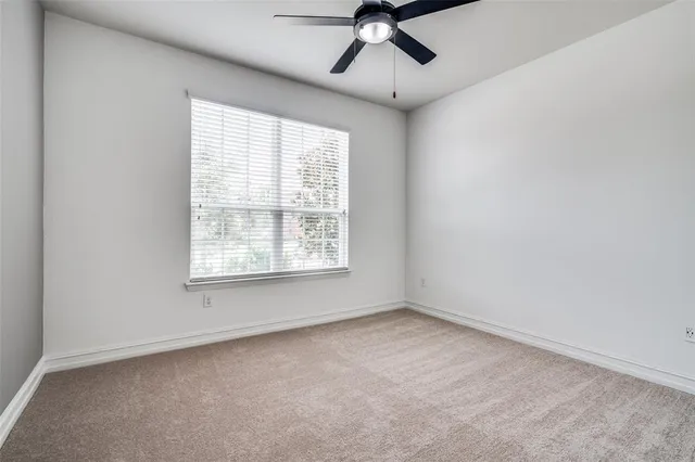 an empty room with a window and a fan