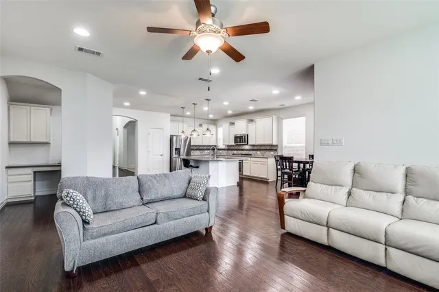 a living room with furniture kitchen view and a chandelier