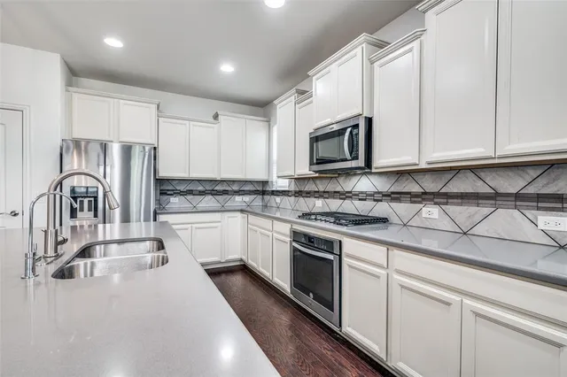 a kitchen with granite countertop white cabinets and stainless steel appliances