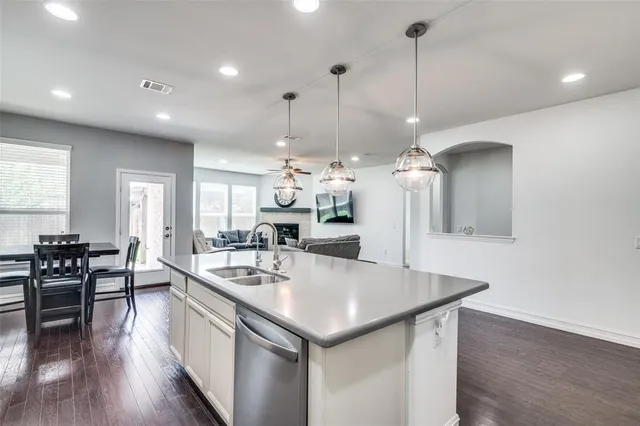 a kitchen with a center island wooden floor stainless steel appliances and living room view