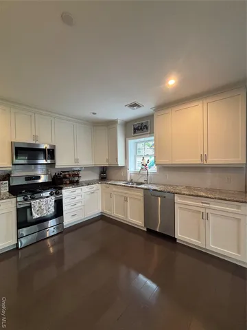 a large white kitchen with granite top and stainless steel appliances