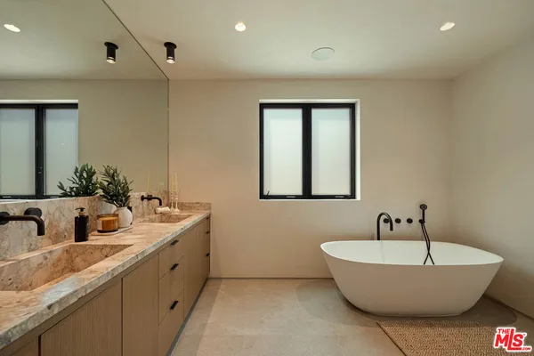 a bathroom with a tub a sink and mirror