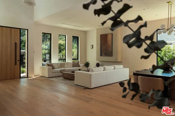 a living room with couches and painting on the wall with a potted plant