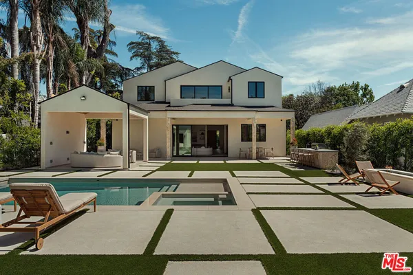 a view of a white house with a small yard and large trees