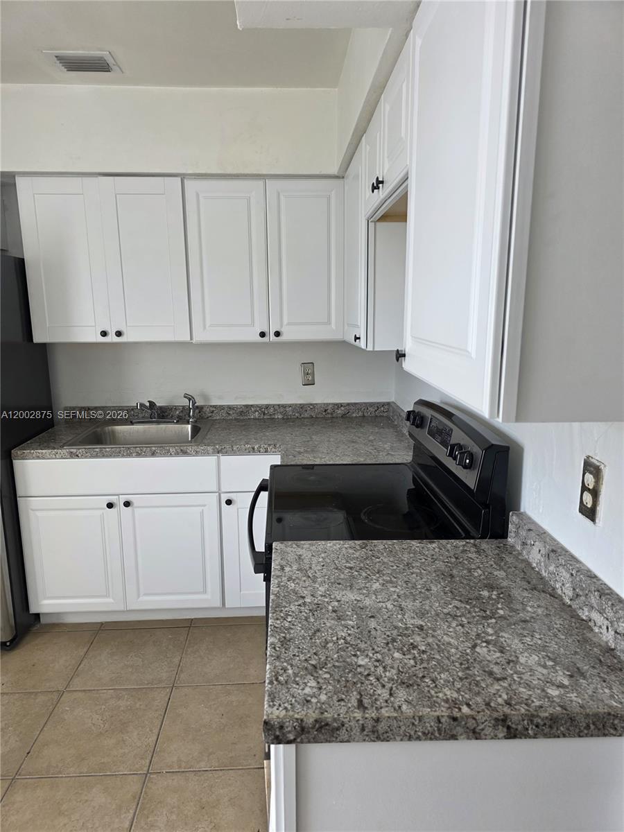 412 Southwest 10th Street, Unit 12 Hallandale Beach, FL 33009 - Photo 5 of 11 a kitchen with stainless steel appliances granite countertop a sink stove and cabinets