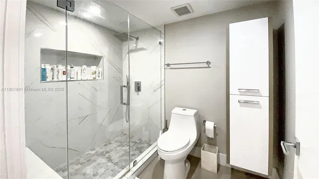 a white toilet sitting next to a bathroom sink and shower