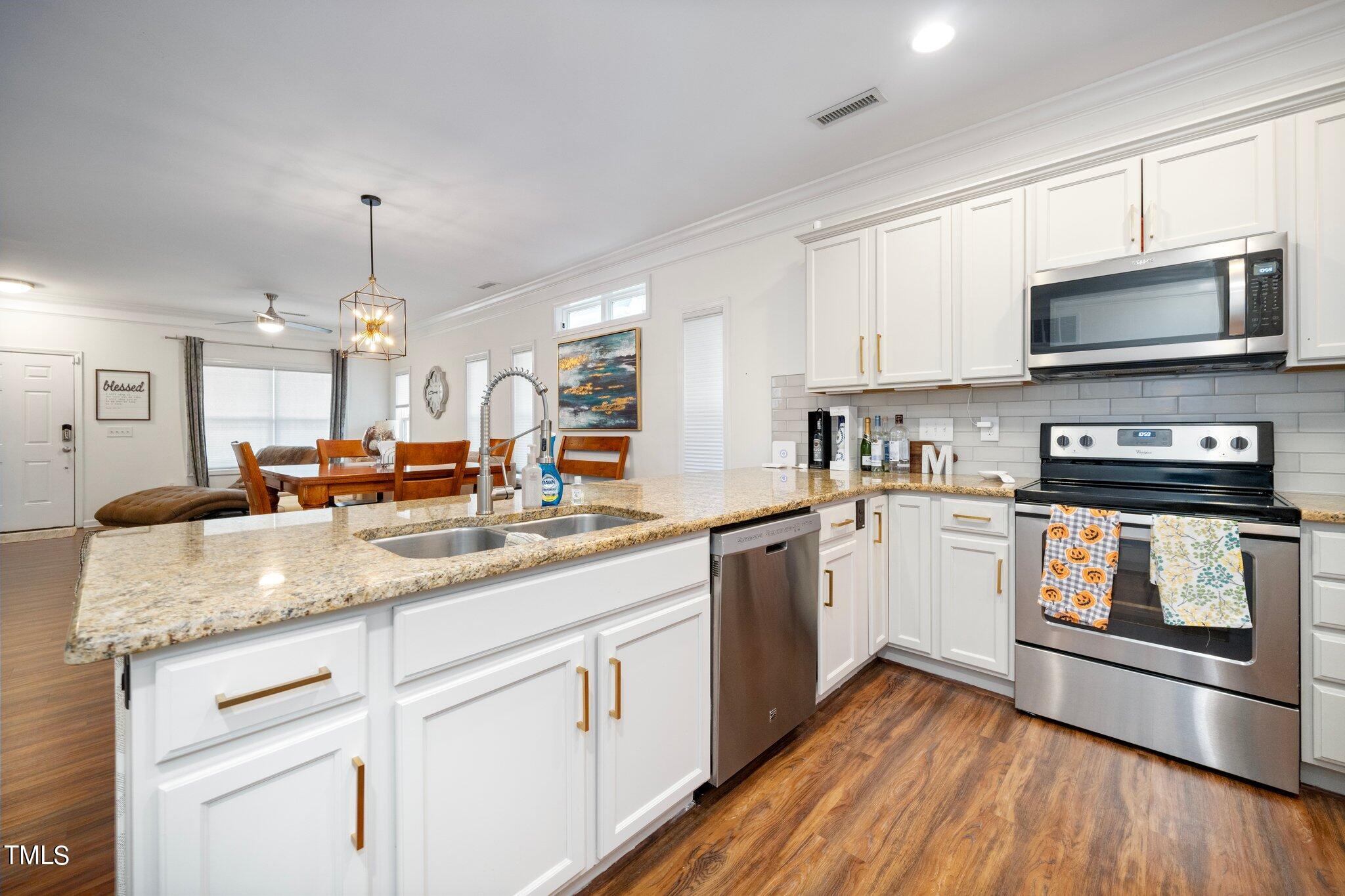 903 Ambergate Station Apex, NC 27502 - Photo 8 of 24 a kitchen with granite countertop a sink stainless steel appliances and white cabinets