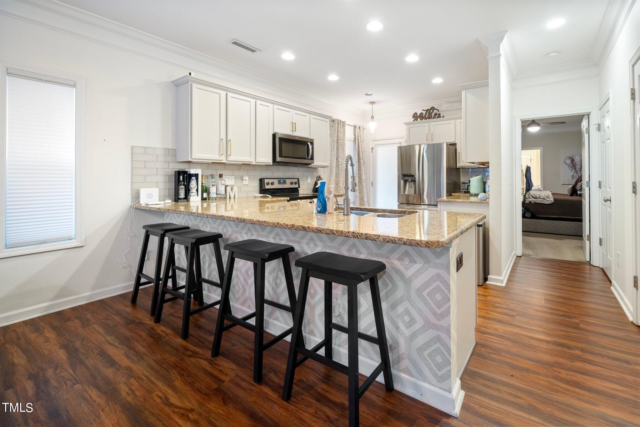 903 Ambergate Station Apex, NC 27502 - Photo 9 of 24 a kitchen with stainless steel appliances granite countertop a stove top oven a sink a refrigerator white cabinets and wooden floor