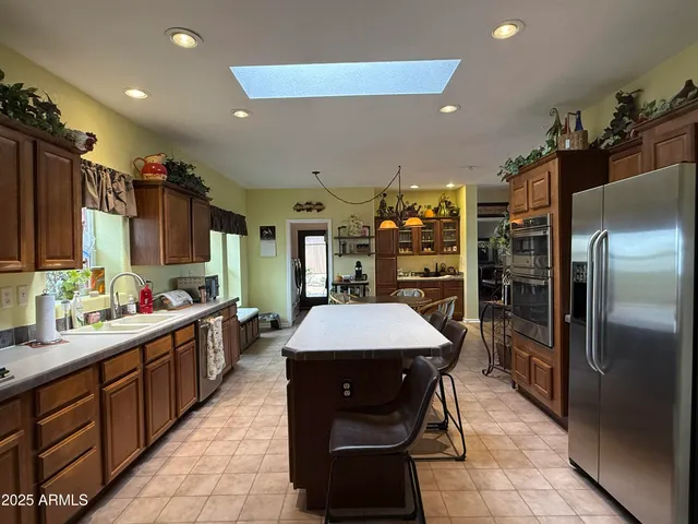 a kitchen with stainless steel appliances kitchen island granite countertop a refrigerator a sink and dishwasher