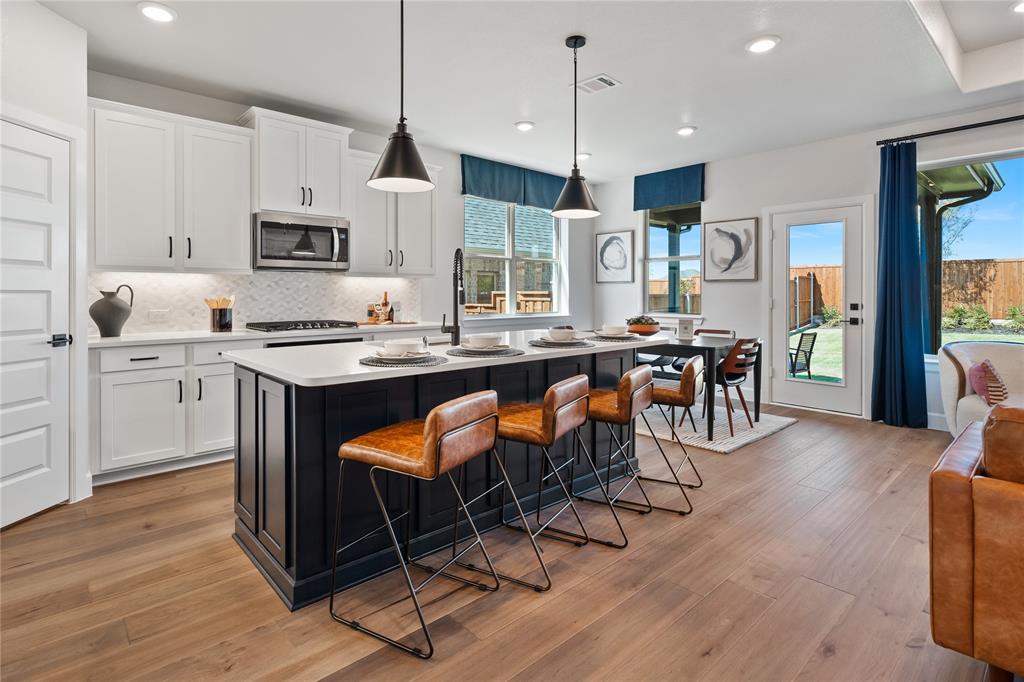 8717 Kentucky Derby Street Pilot Point, TX 76258 - Photo 3 of 18 a kitchen with stainless steel appliances kitchen island granite countertop a table chairs sink and cabinets